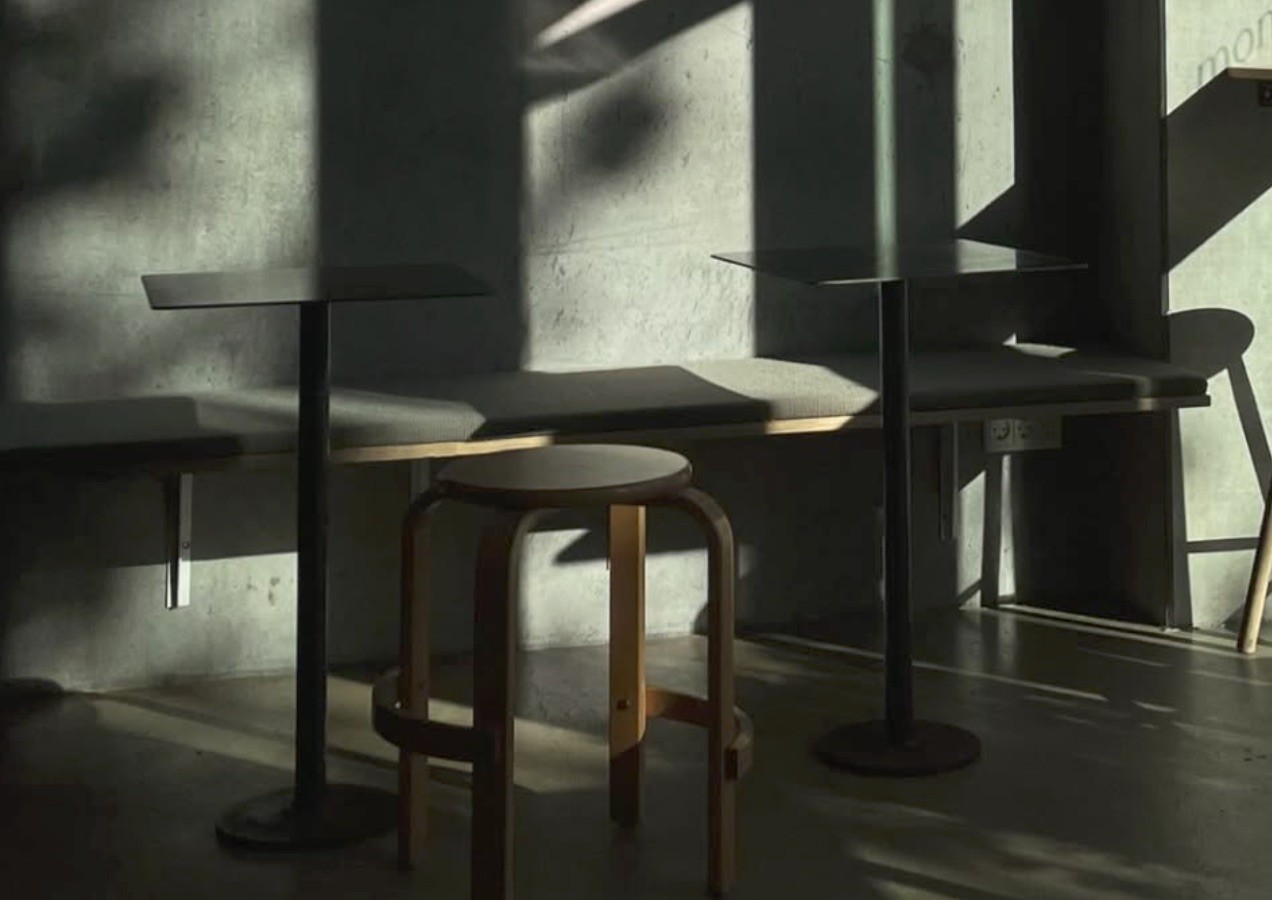 Low afternoon light casting long shadows across cafe stools and standing tables at Monk