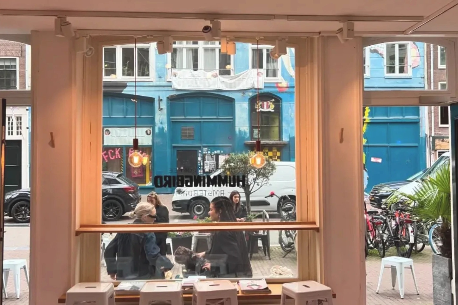 The view from inside Hummingbird's window seat, the shop's own lettering on the glass and the Spuistraat street scene beyond