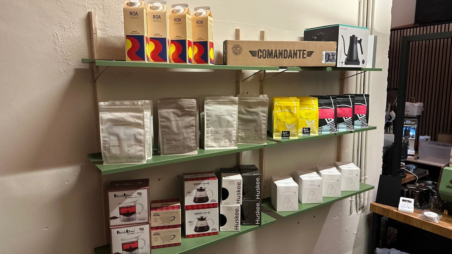 Retail shelves stocked with Uncommon and Rum Baba beans beside brewing gear boxes