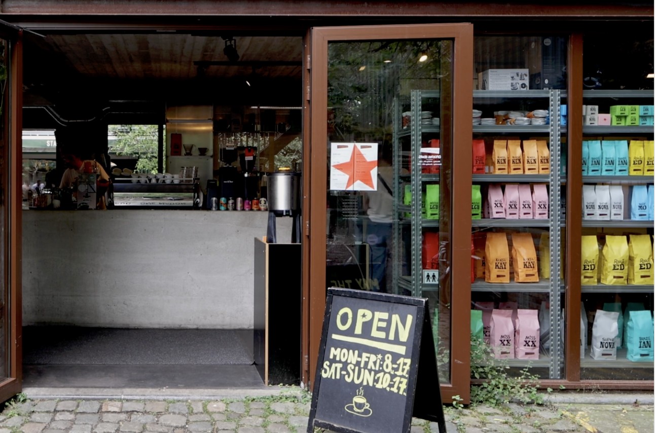 The open garage style storefront of Caffènation with colorful retail coffee bags stacked on shelves