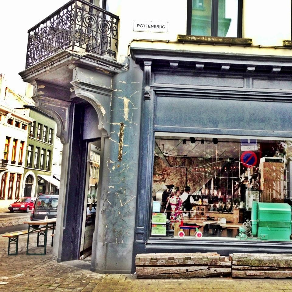 The corner storefront of Normo beneath a wrought iron balcony and the Pottenbrug street sign in Antwerp's historic center