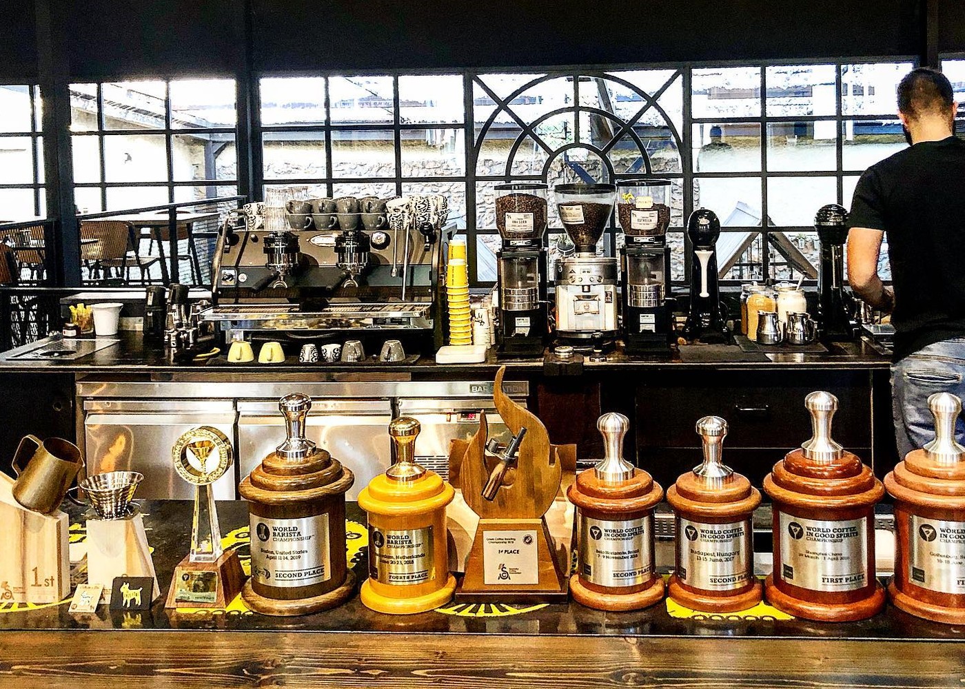 A row of world championship trophies lined up on the counter beneath the espresso machine at The Underdog