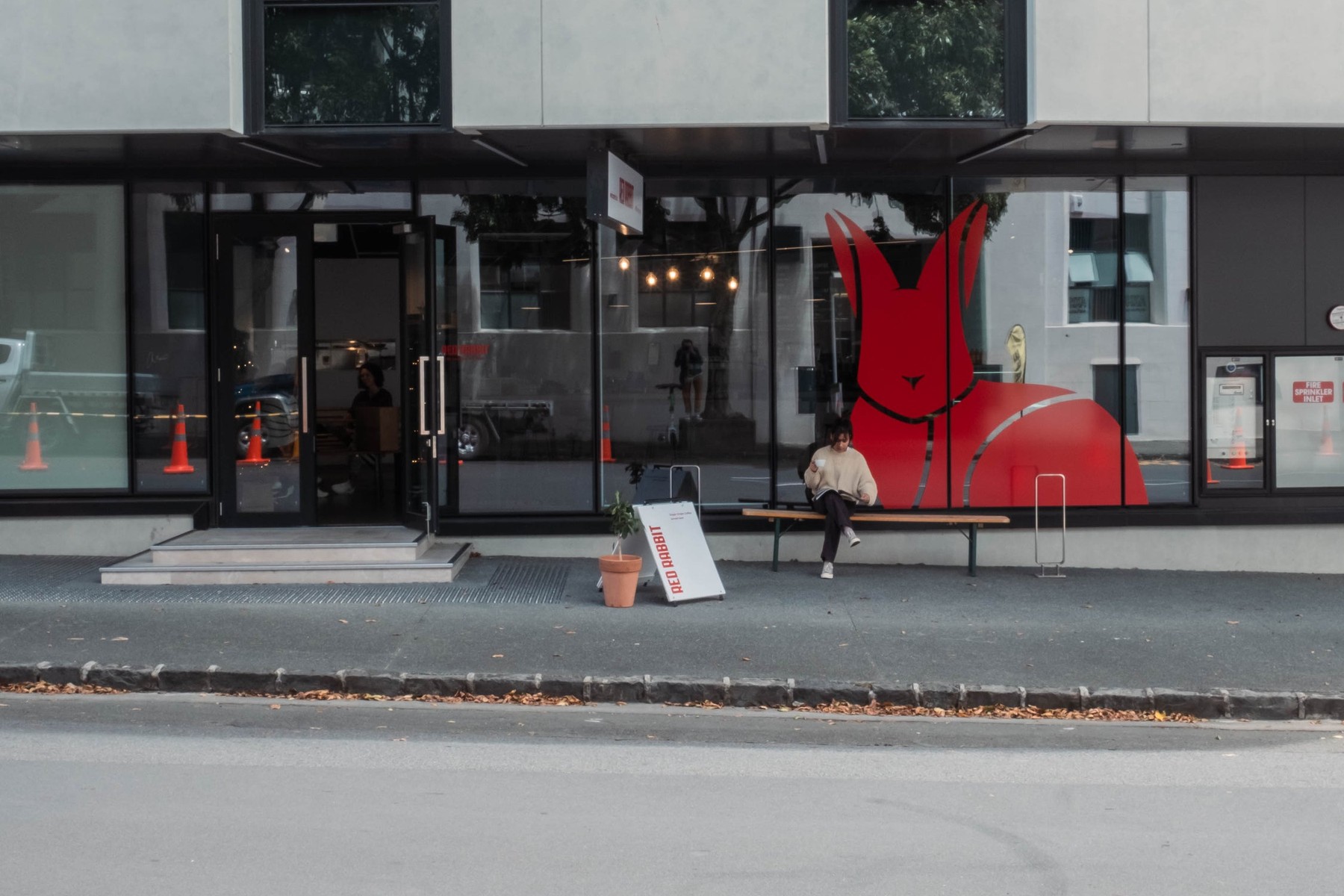 The Red Rabbit Coffee shopfront on Saint Georges Bay Road in Parnell, a large red rabbit graphic across the glass and a timber bench outside