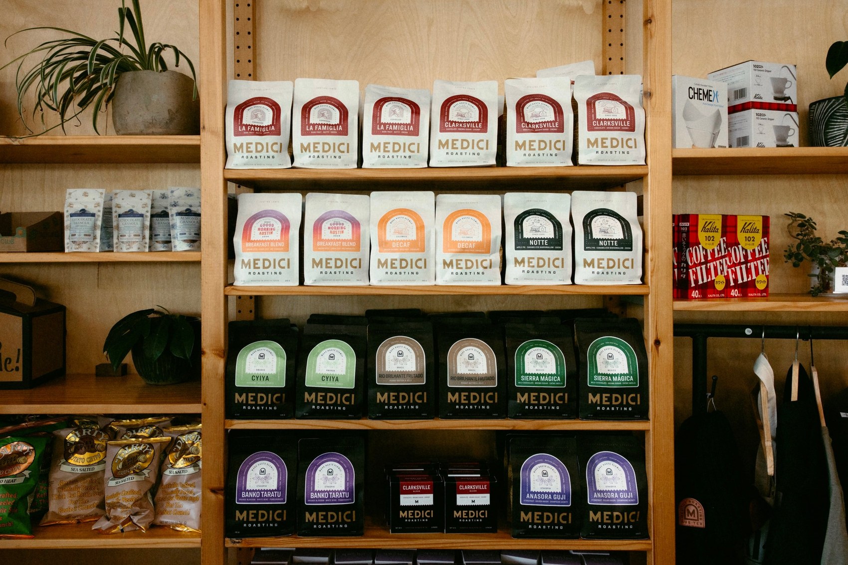 A wooden retail shelf stocked with branded Medici Roasting bean bags