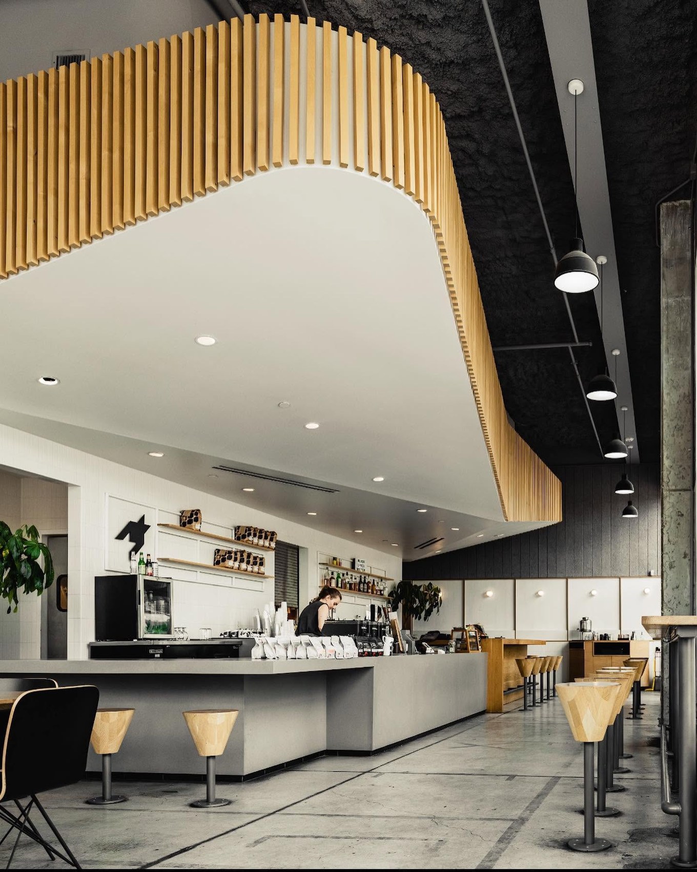 The curved wood slat ceiling over the concrete espresso bar at Houndstooth Coffee
