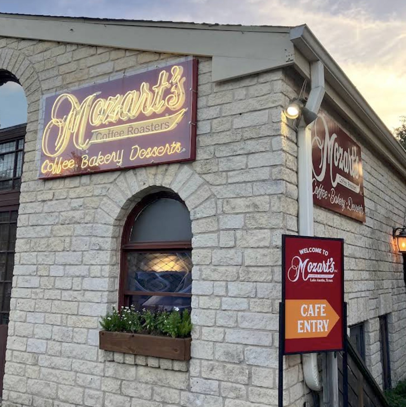 The stone building exterior with the neon Mozart's Coffee Roasters sign
