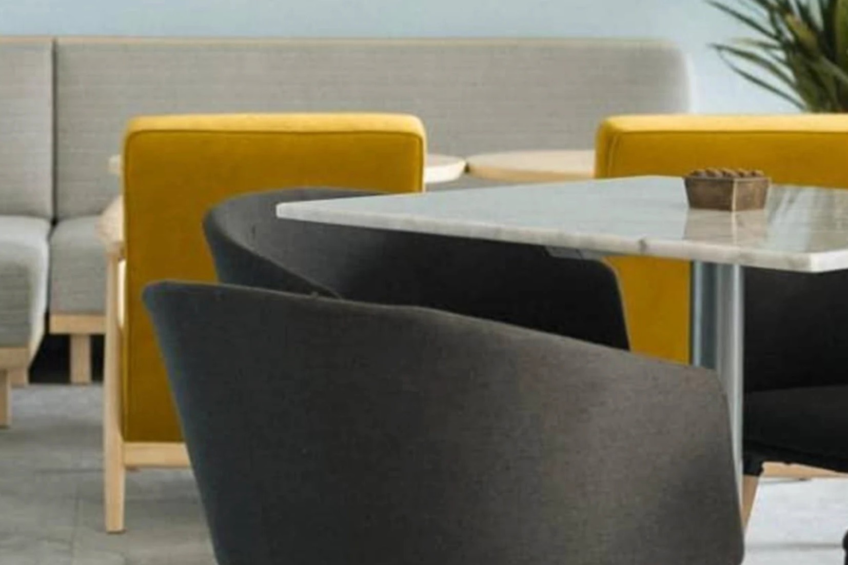 A grey banquette, mustard and charcoal armchairs and a marble topped table in the dining room at Rocket Coffeebar