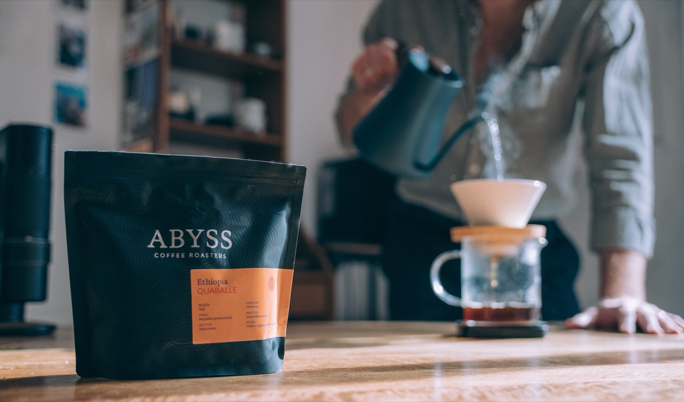 A bag of Abyss Coffee Roasters Ethiopia beans on a table beside a pour-over brew in progress