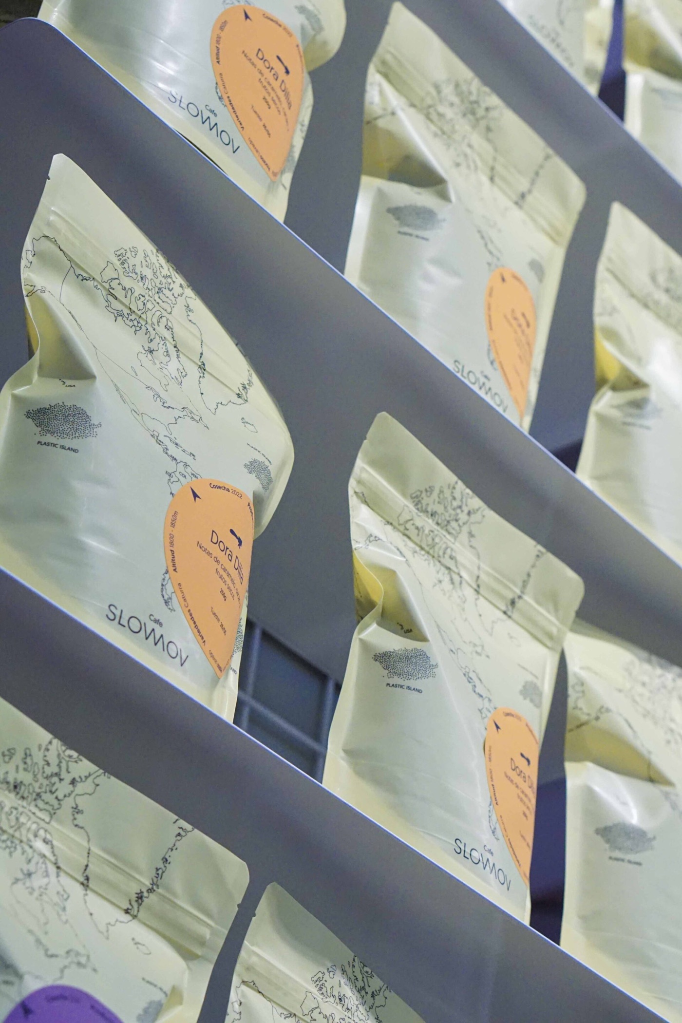 Rows of SLOWMOV branded coffee bags on a wall mounted display shelf