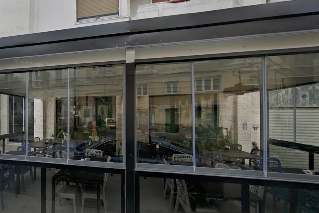 The glassed-in terrace seating at Pierre Café on Piazza Cavour, tables visible through the storefront windows
