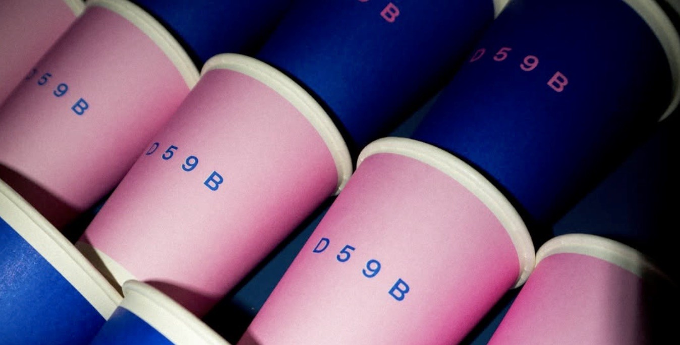 Rows of pink and blue branded D59B paper cups lined up in close-up
