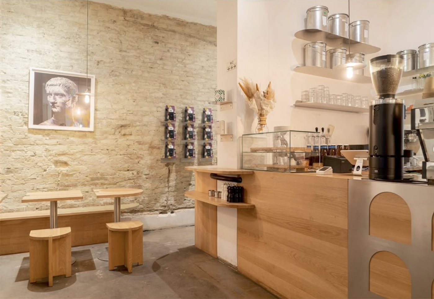 Inside Silo Coffee, exposed brick wall with a framed portrait, wooden stools, and the espresso counter