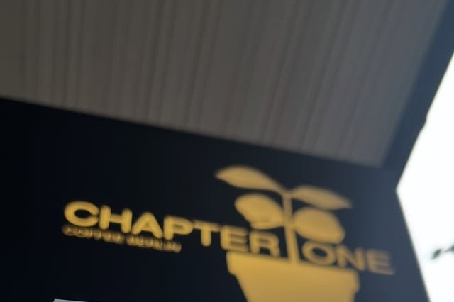 Chapter One's illuminated sign and a retail coffee bag price tag reading Apricotini, heirloom, red honey