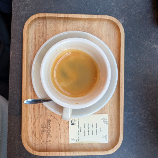 An espresso on a wooden Mood24 branded tray beside a card listing the bean's origin and tasting notes