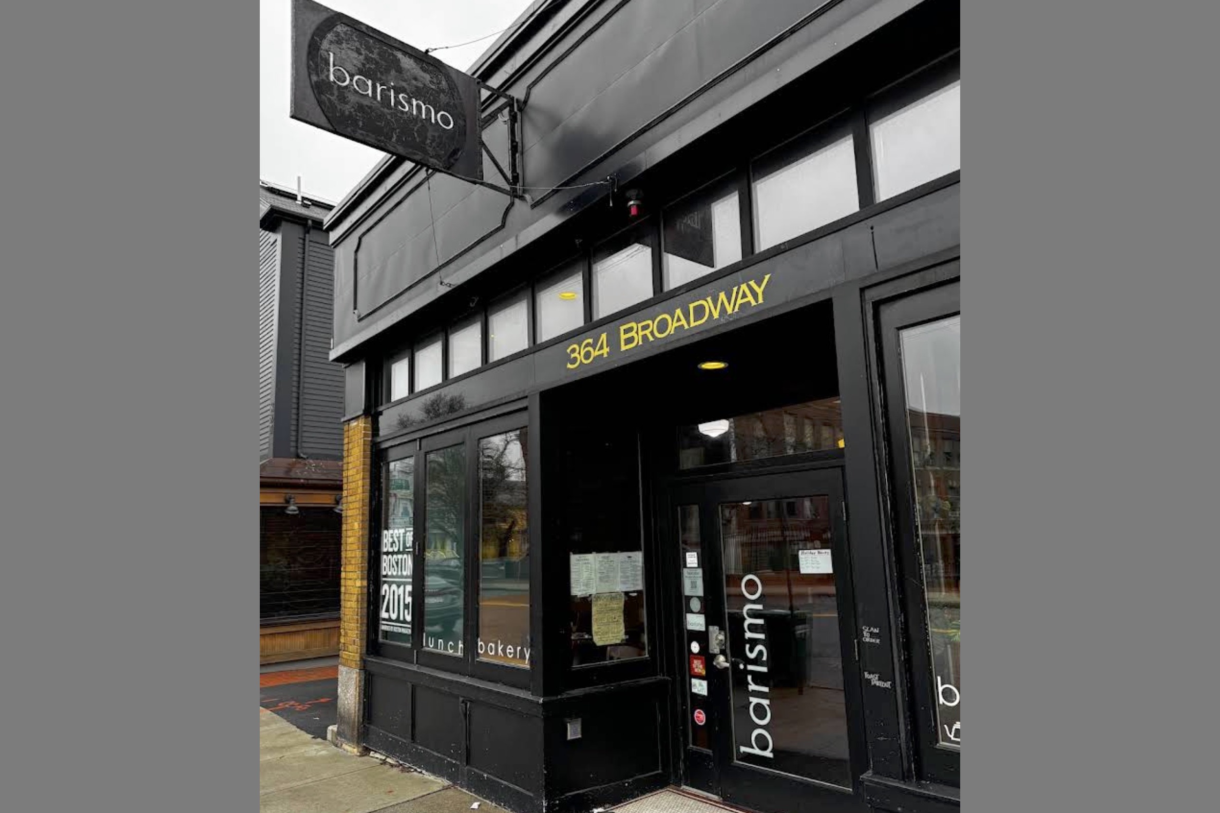 The black storefront at 364 Broadway with the hanging barismo sign and a Best of Boston 2015 window decal