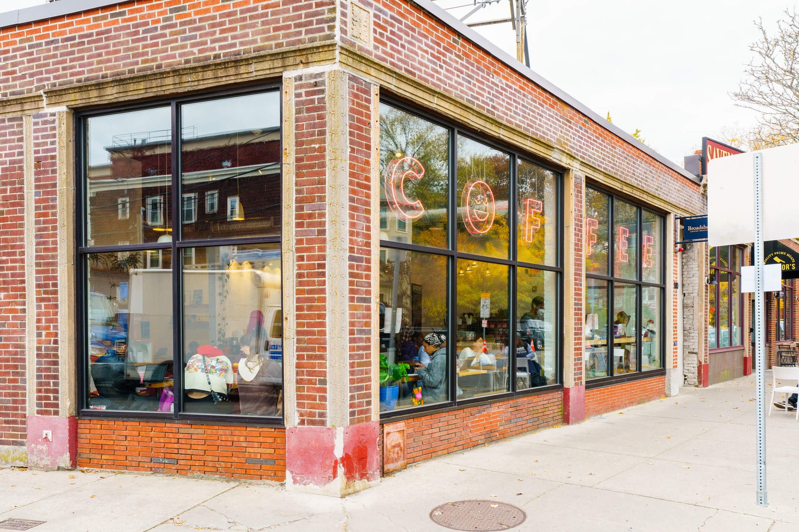 The brick corner storefront of Broadsheet Coffee Roasters with a neon COFFEE sign in the window