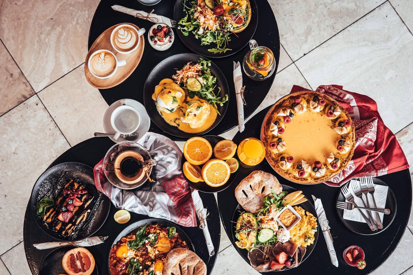 An overhead spread of Café Placzek's brunch menu, including eggs benedict, shakshuka, a fruit tart, and coffee