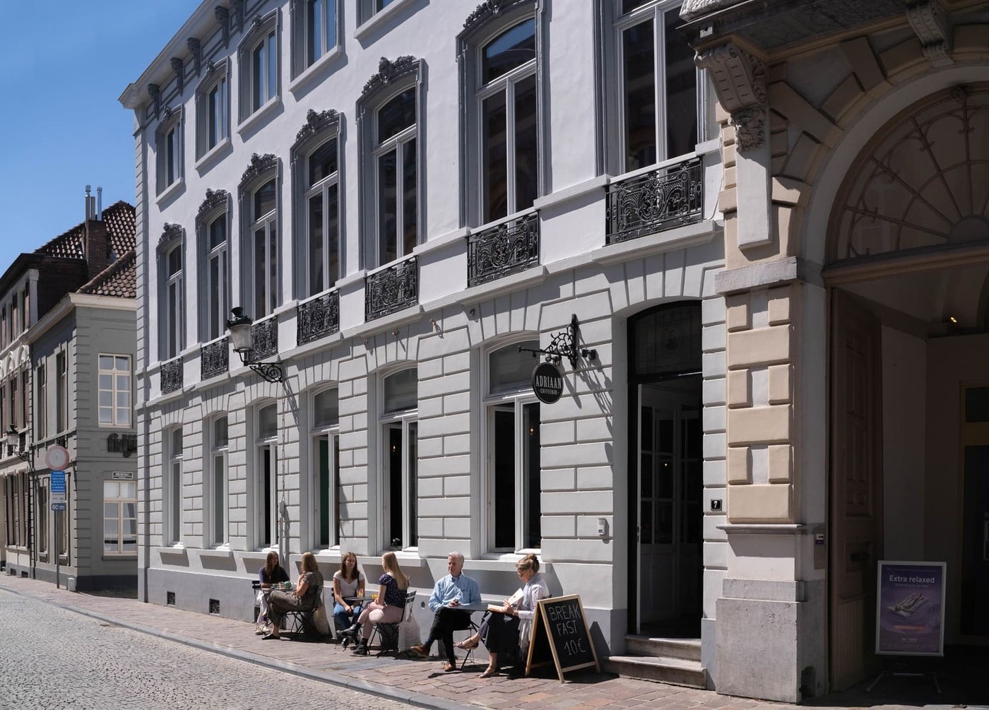 The neoclassical facade of Coffeebar Adriaan on Adriaan Willaertstraat with guests seated at outdoor tables