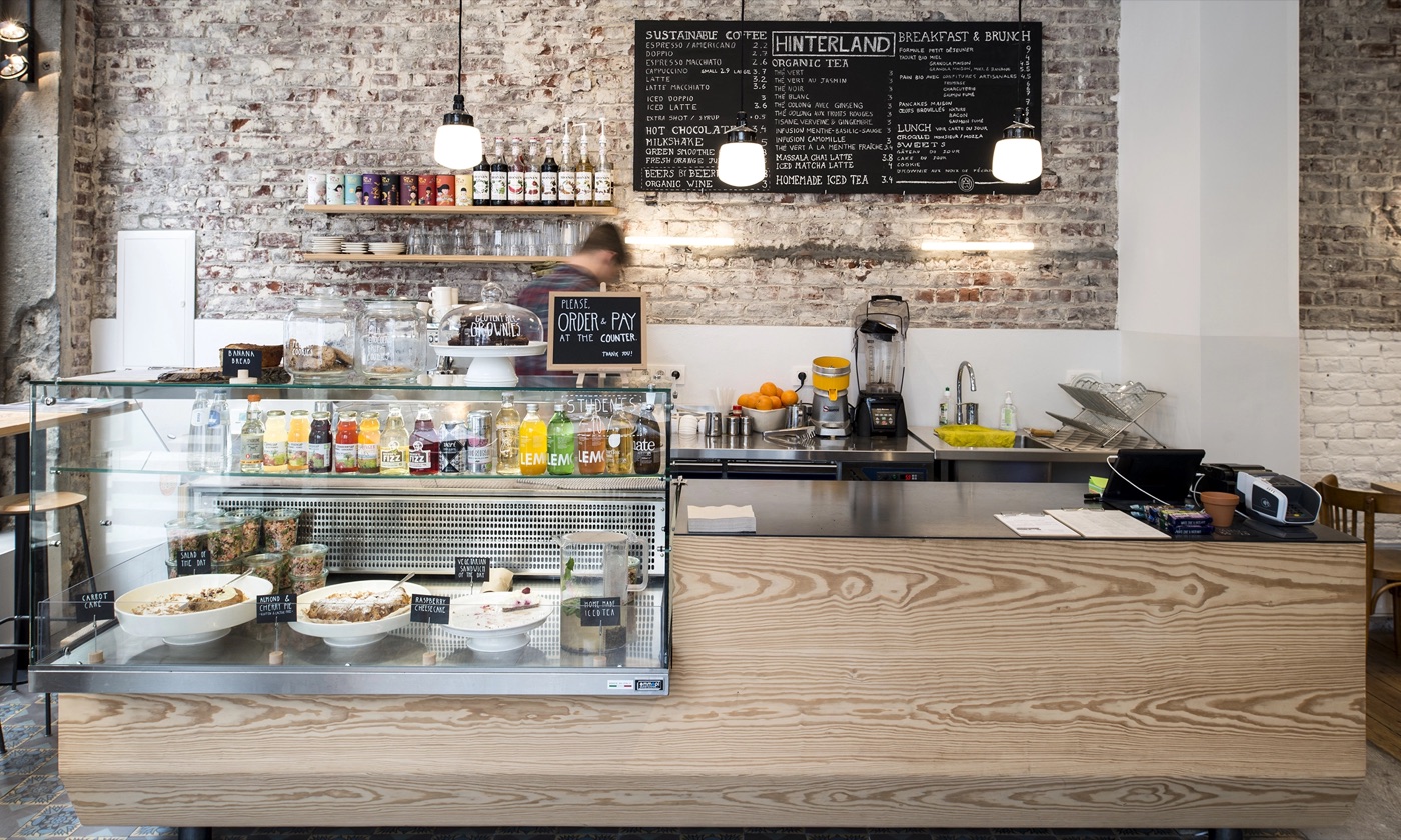 The exposed brick counter and chalkboard menu at Hinterland, with a glass pastry case in the foreground