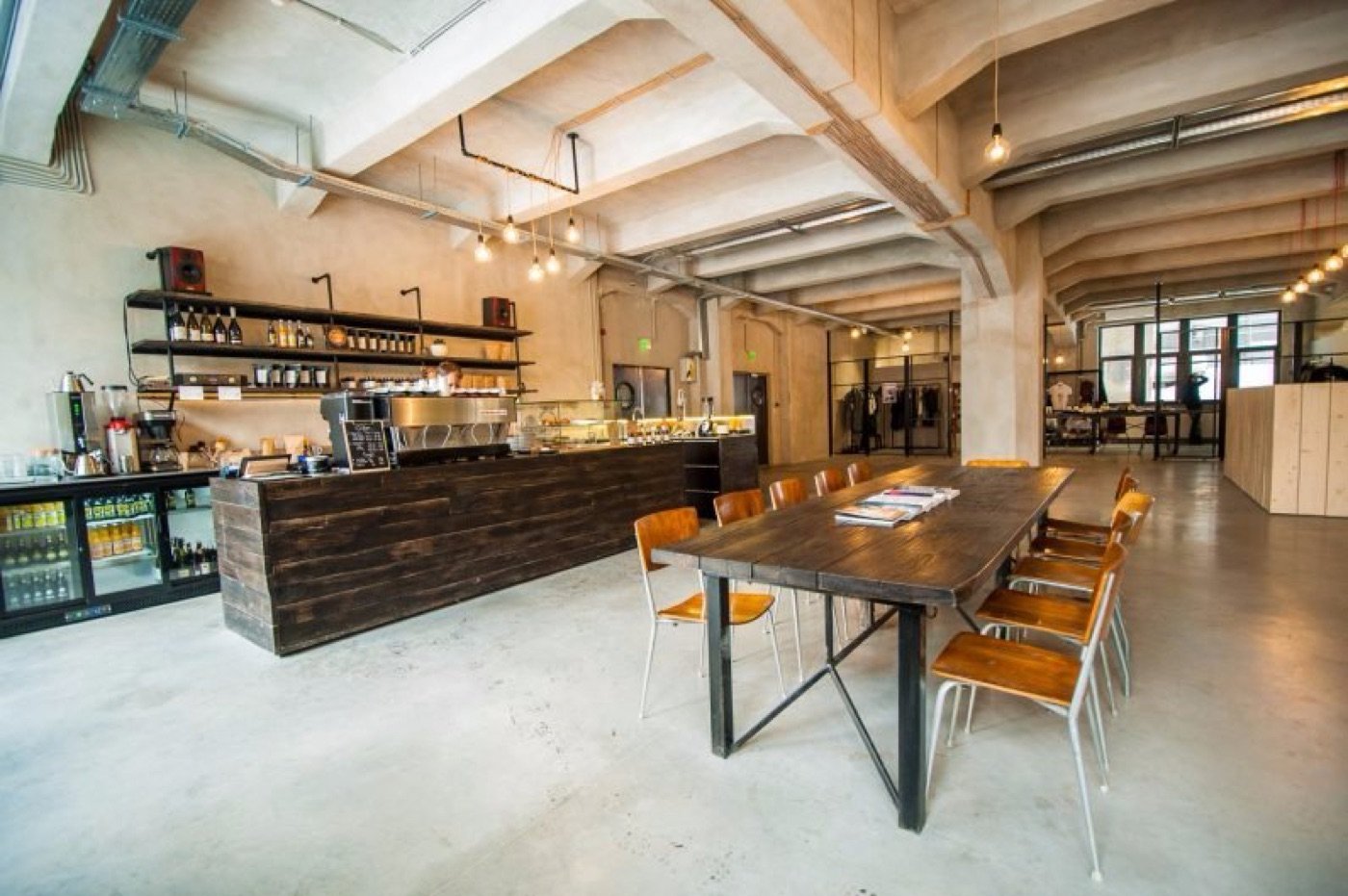 The industrial interior of Beans & Dots inside Palatul Universul, with exposed concrete beams and a long communal table