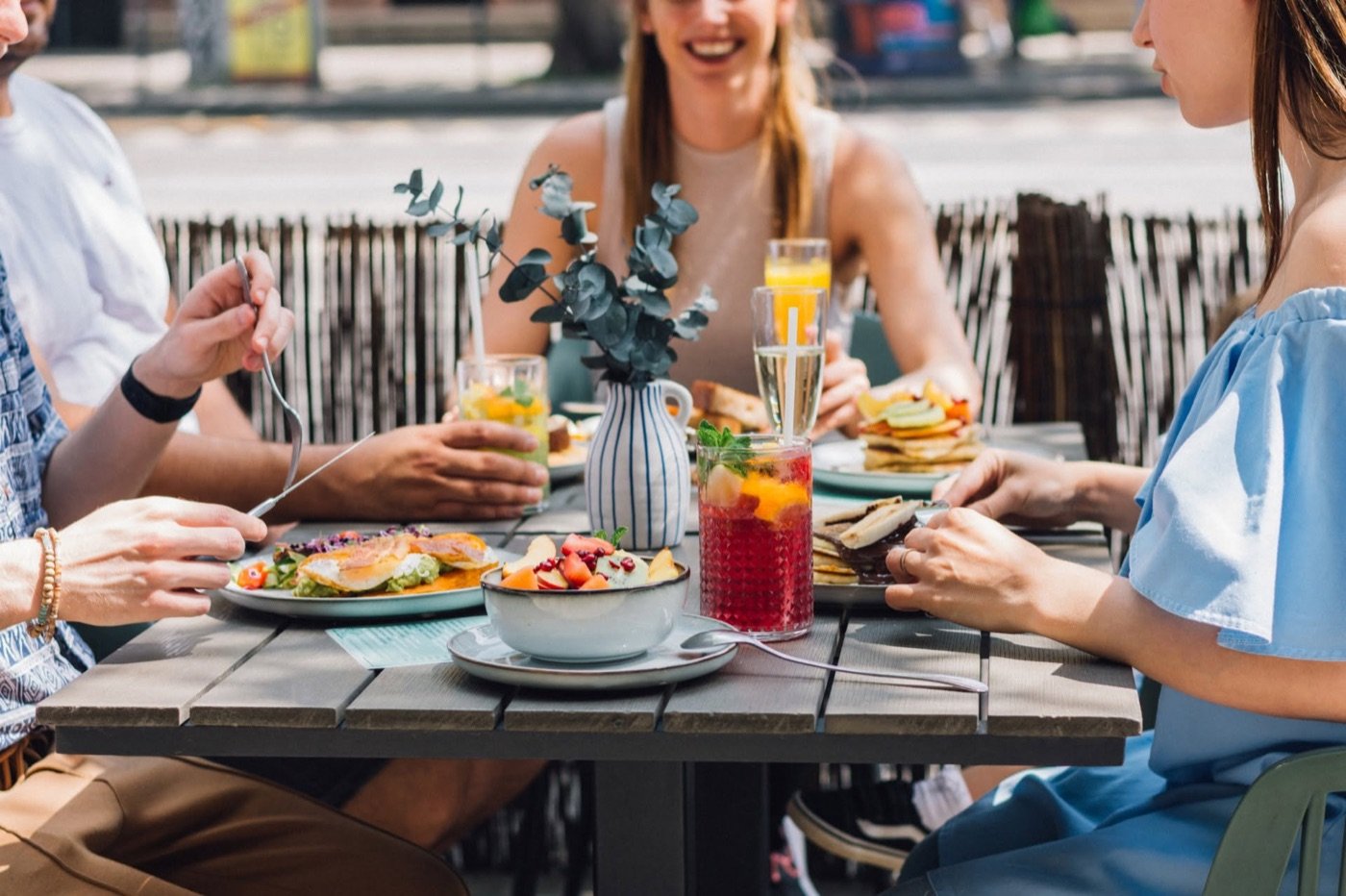 Friends sharing brunch and drinks at an outdoor table at Budapest Baristas