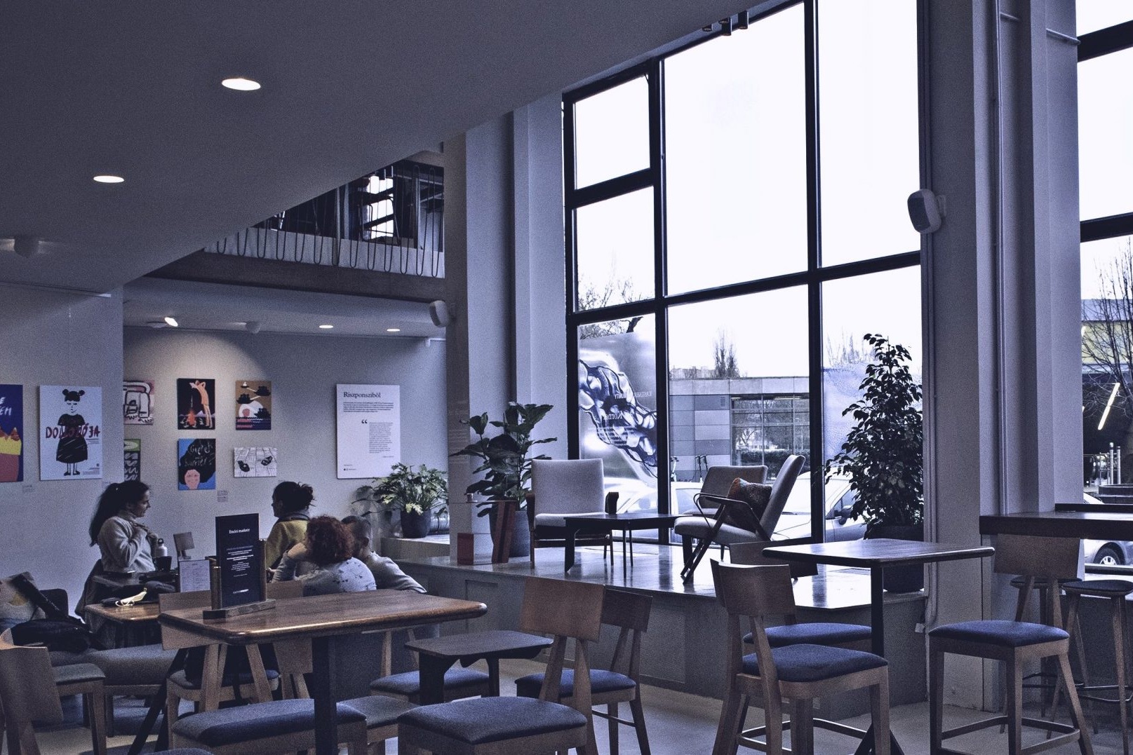 The floor to ceiling windows, elevated podium seating, and gallery wall inside Kastner Kommunity