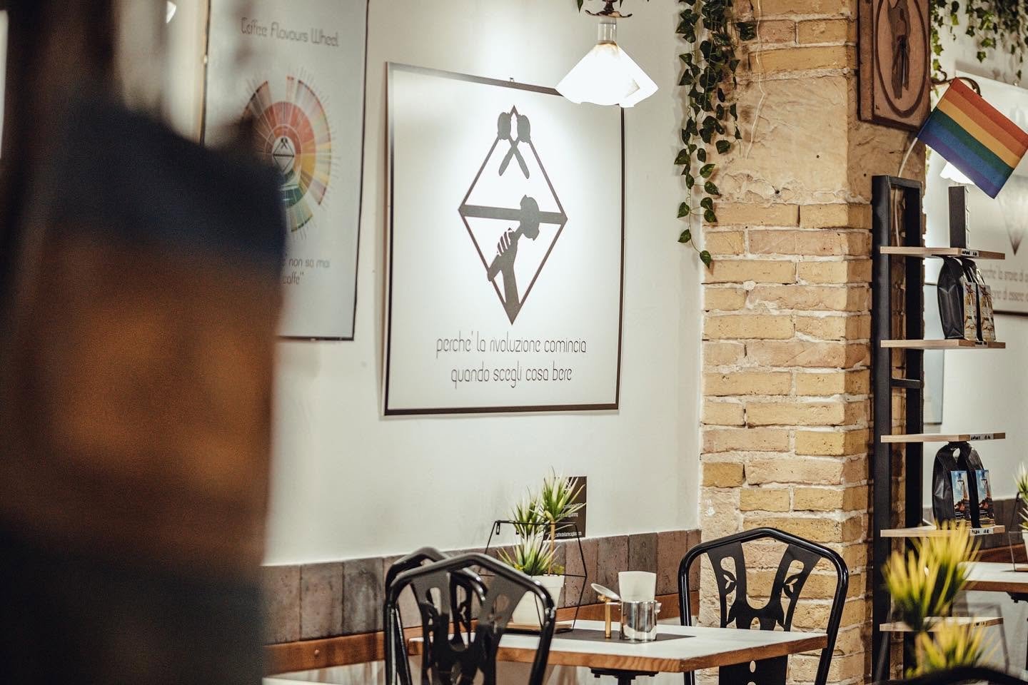The interior of Caffè dell'Arte with exposed brick, art on the walls, and bagged coffee for sale on a wall shelf