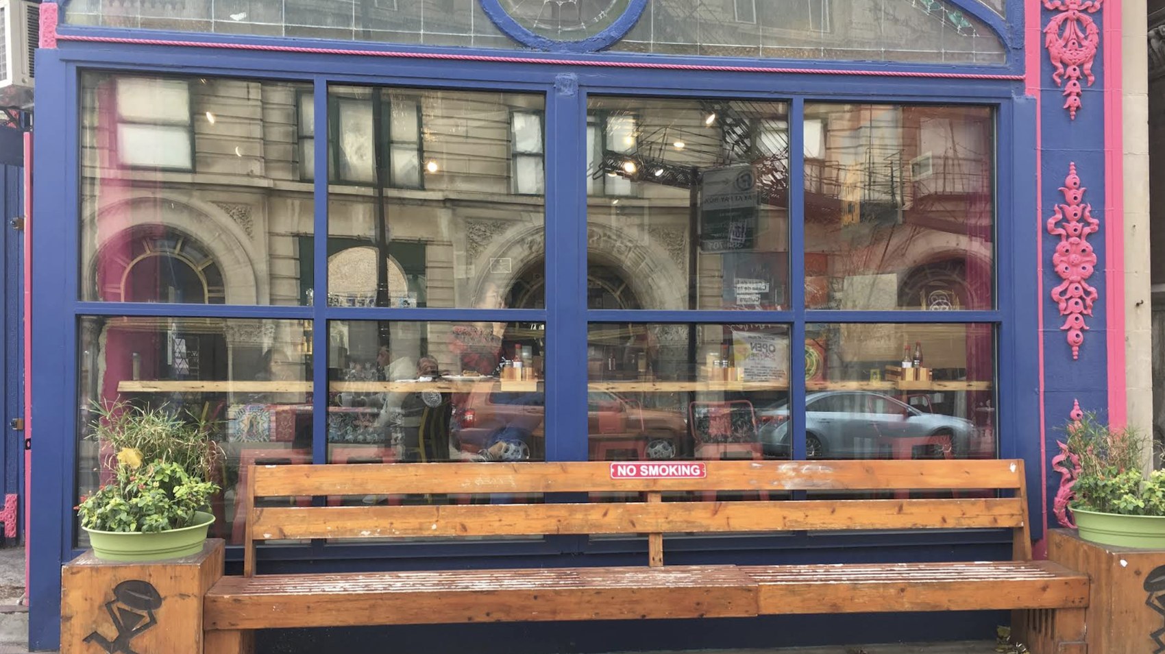 The blue and pink storefront of Café Jumping Bean with the wooden bench out front