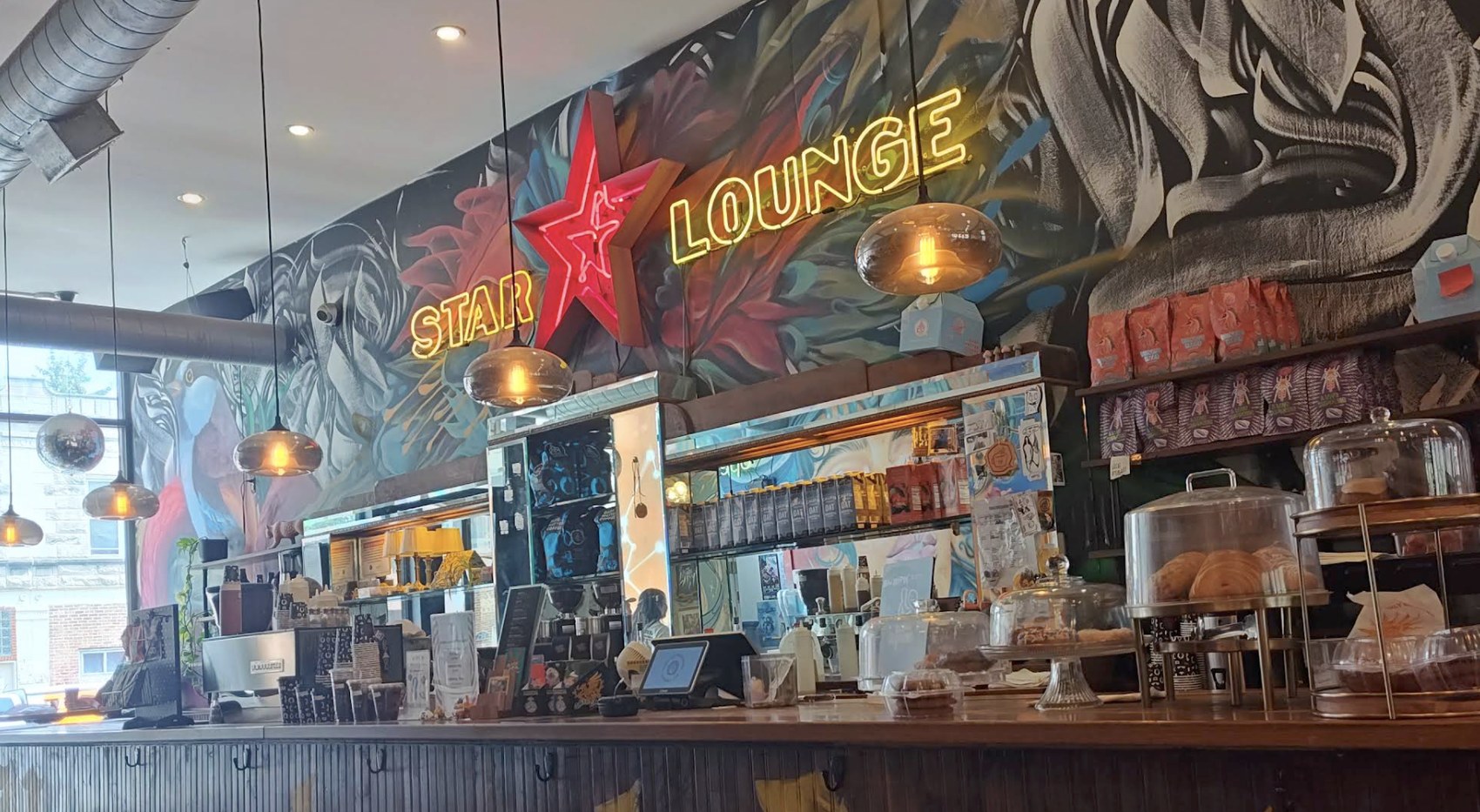 The counter beneath the neon Star Lounge sign and mural at Dark Matter Coffee