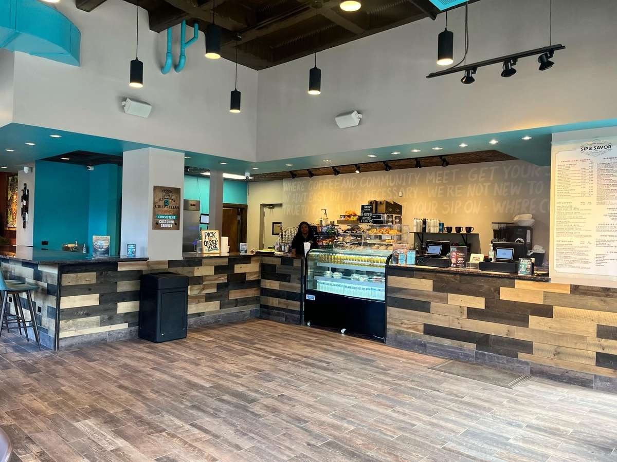 The counter and pastry case at Sip & Savor beneath the shop's painted wall text