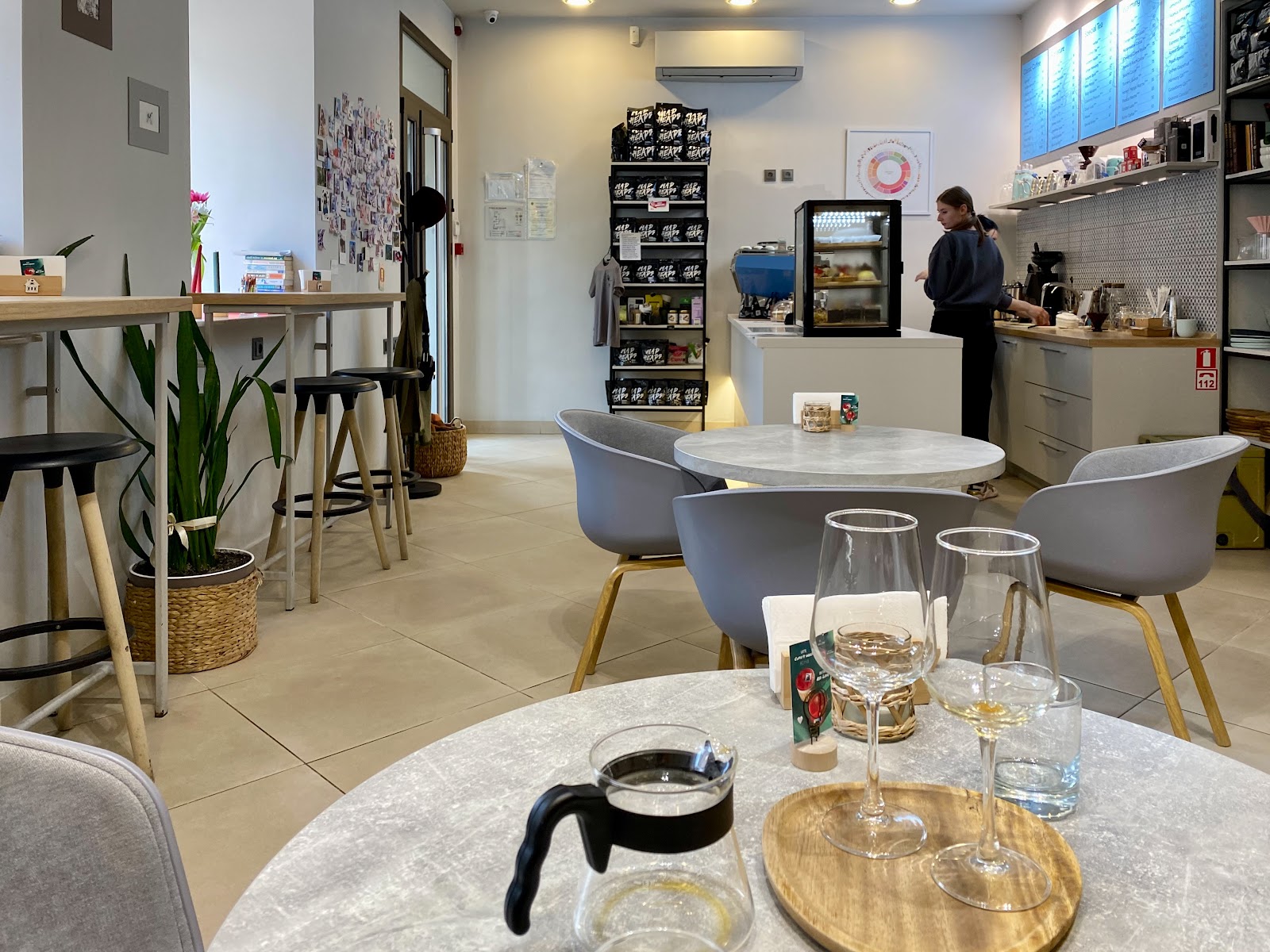 The bright interior of Pasio Coffee with round marble tables and a barista working at the counter