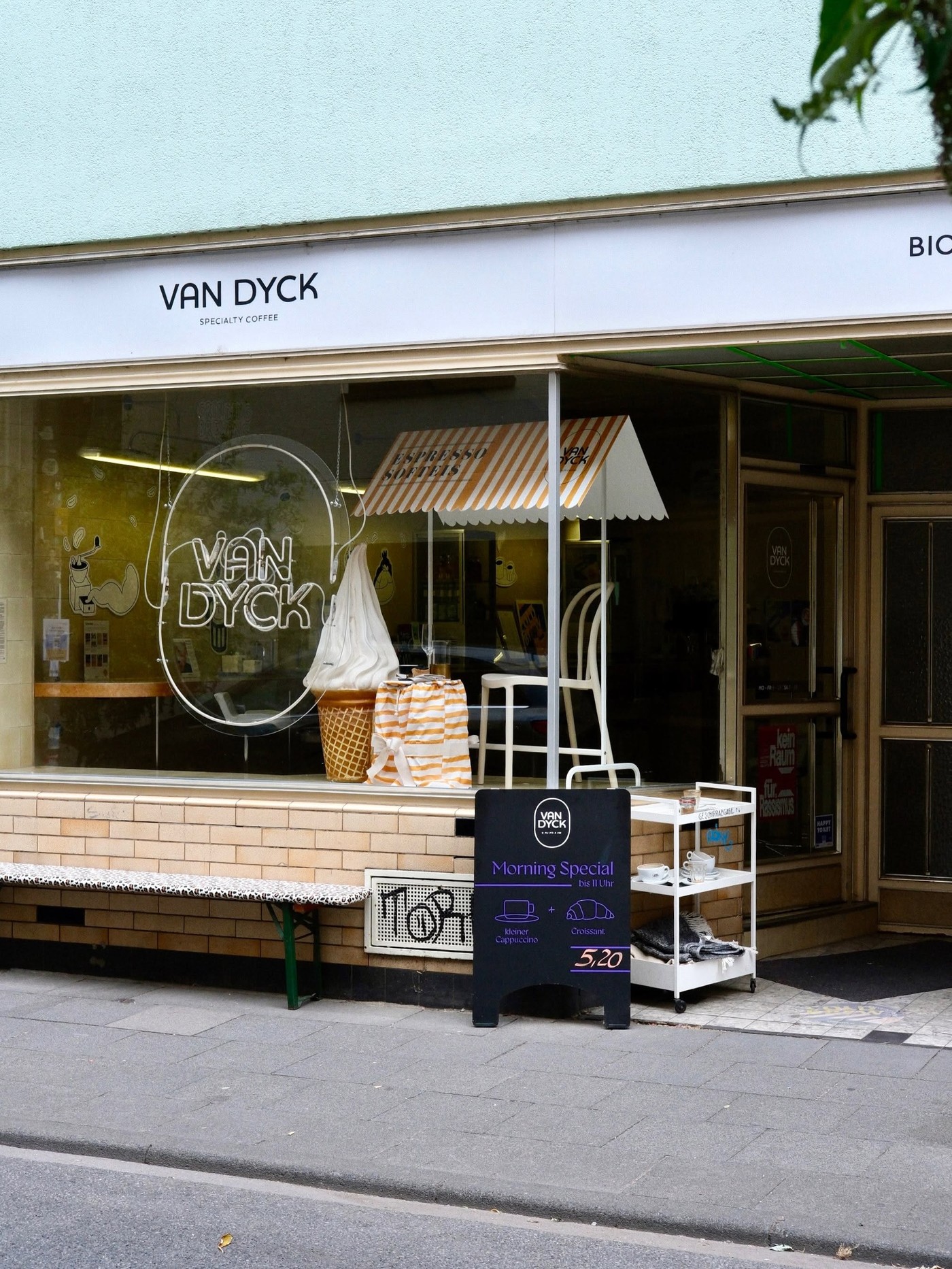 The Van Dyck Specialty Coffee storefront window with its neon logo, an espresso soft serve display, and a Morning Special sandwich board out front