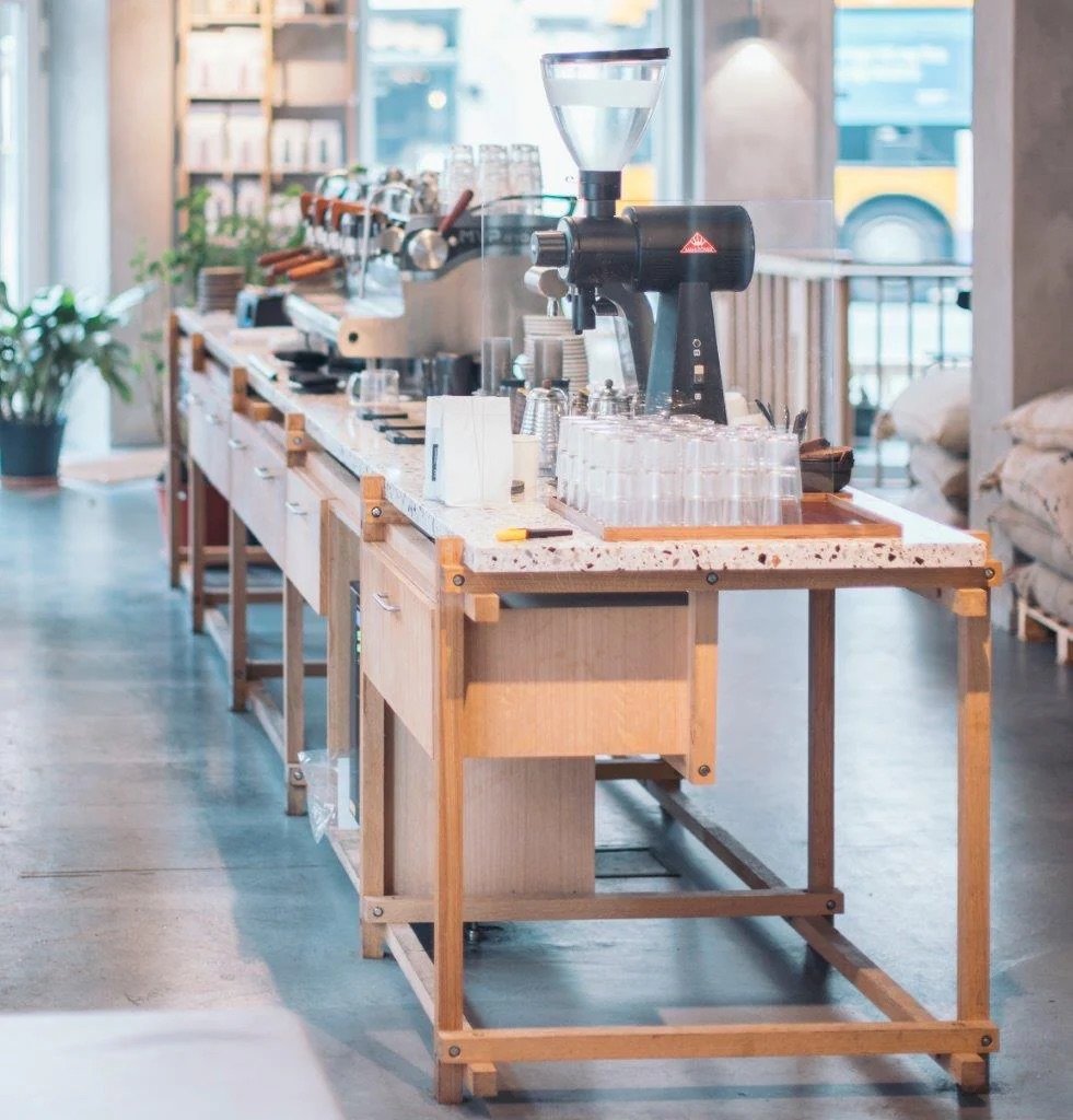 The long oak-and-terrazzo counter at Andersen & Maillard, concrete floor and plants either side