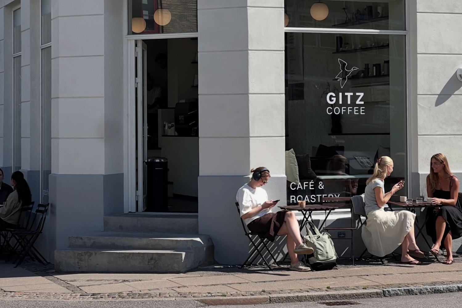 The corner storefront of GITZ Coffee on Landskronagade, the sandblasted logo on the window above outdoor tables