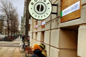 The round ROAST Coffee storefront sign on Vestmannagade above a 'coffee bar and roastery' placard, with outdoor bench seating below