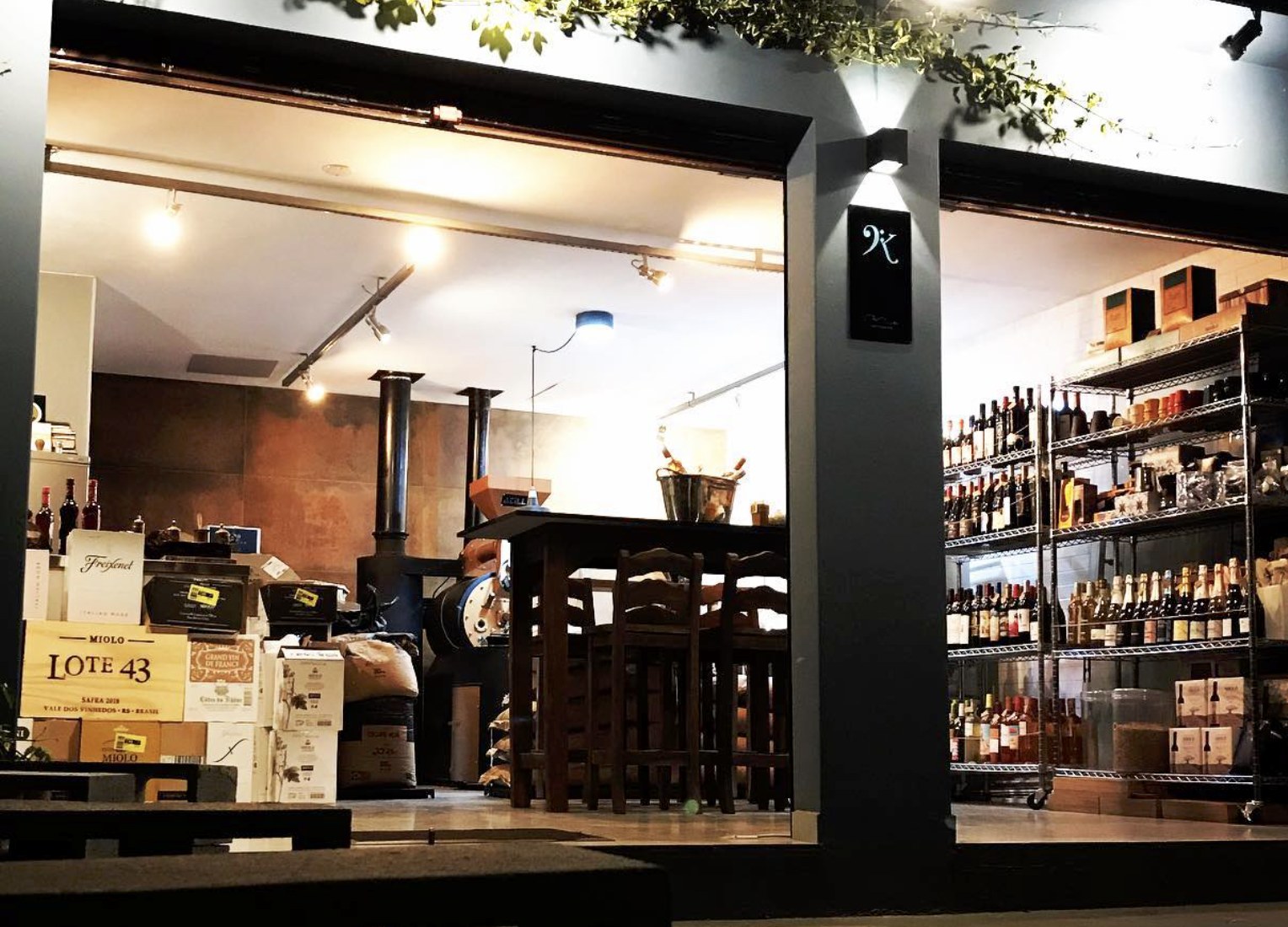 The storefront at Kaffe-Kantate at night, with the roaster and wine shelving visible