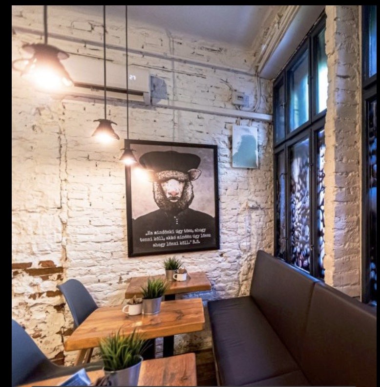 A seating nook at Black Sheep Microroastery, with exposed brick, industrial pendant lights, and a framed black sheep portrait on the wall