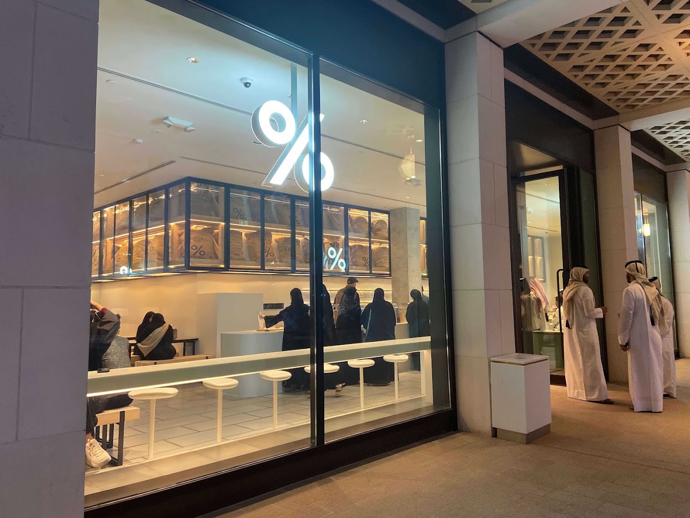 The illuminated percent sign and coffee sack display at % Arabica's storefront window in Msheireb Downtown Doha