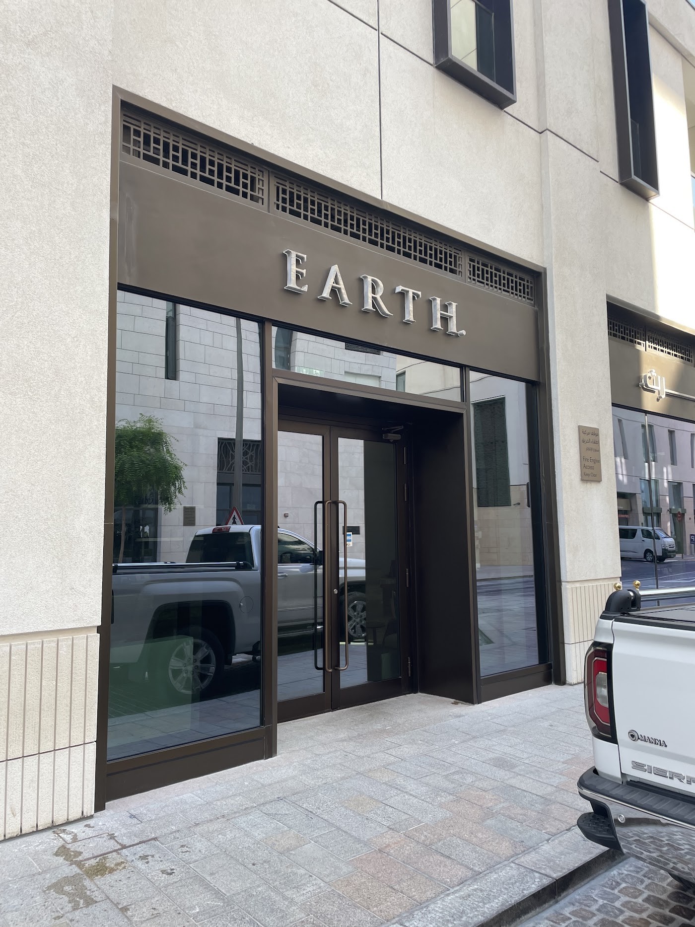 The Earth storefront entrance with its metal signage set into a limestone facade in Msheireb Downtown