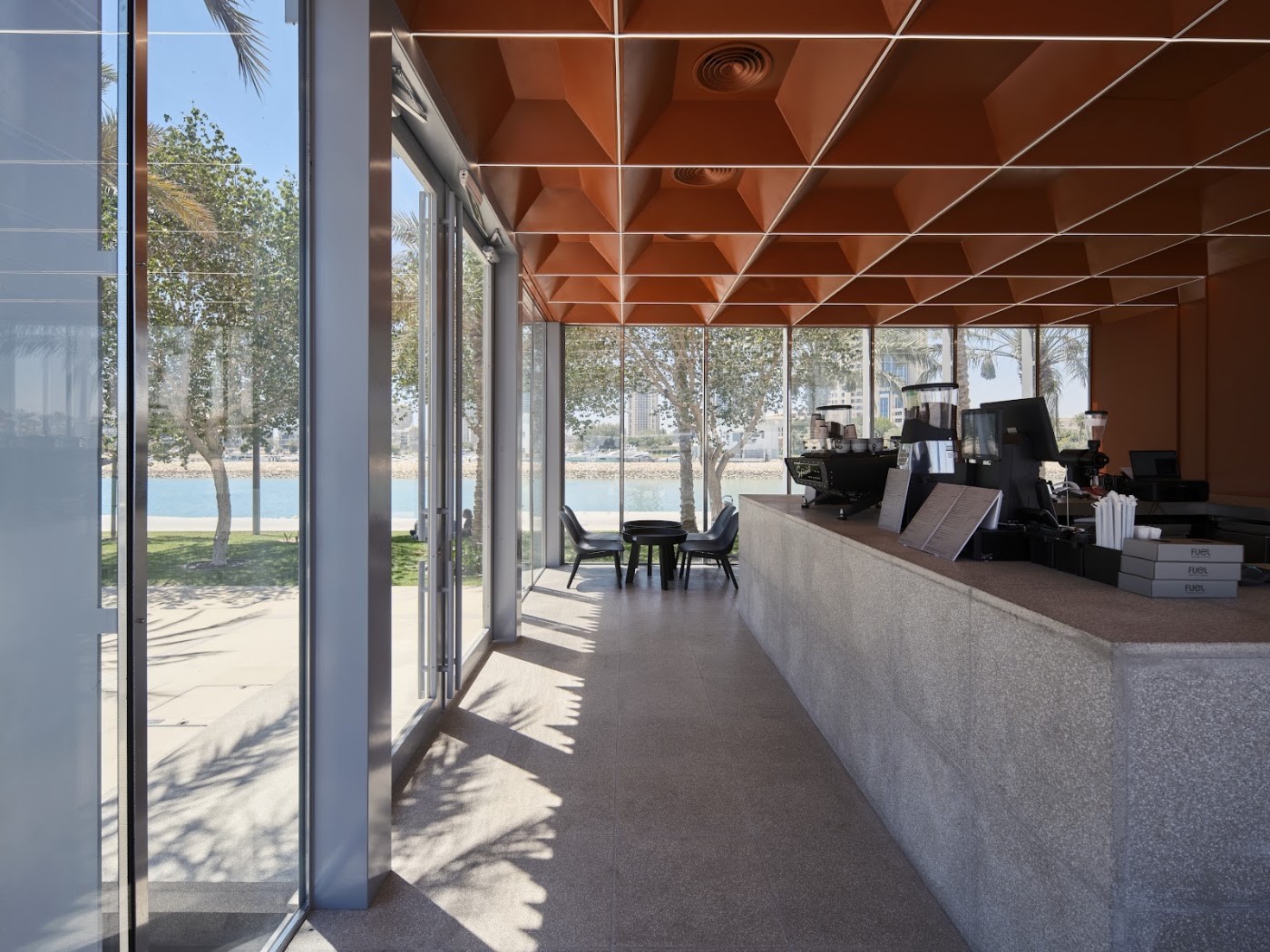 The terracotta ceilinged counter at Fuel's Lusail marina branch with floor to ceiling glass overlooking the promenade and water