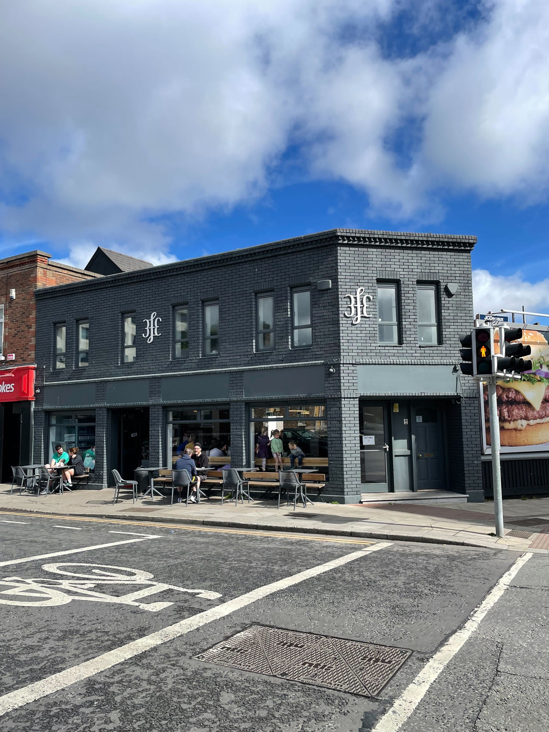 The dark brick 3fe building on Grand Canal Street, outdoor tables out front under a wide blue sky