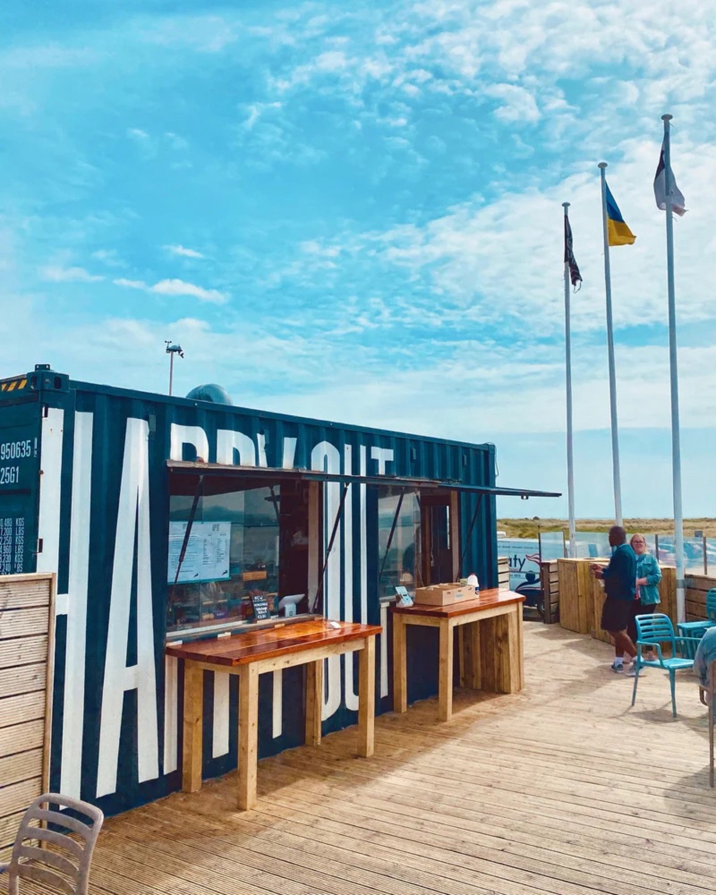 The Happy Out shipping container cafe on the Bull Island boardwalk, flags flying against a blue sky