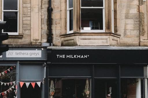 The Milkman's dark shopfront on Cockburn Street with THE MILKMAN lettering on the fascia below a carved sandstone bay window, next to the neighboring Tethera Greys sign