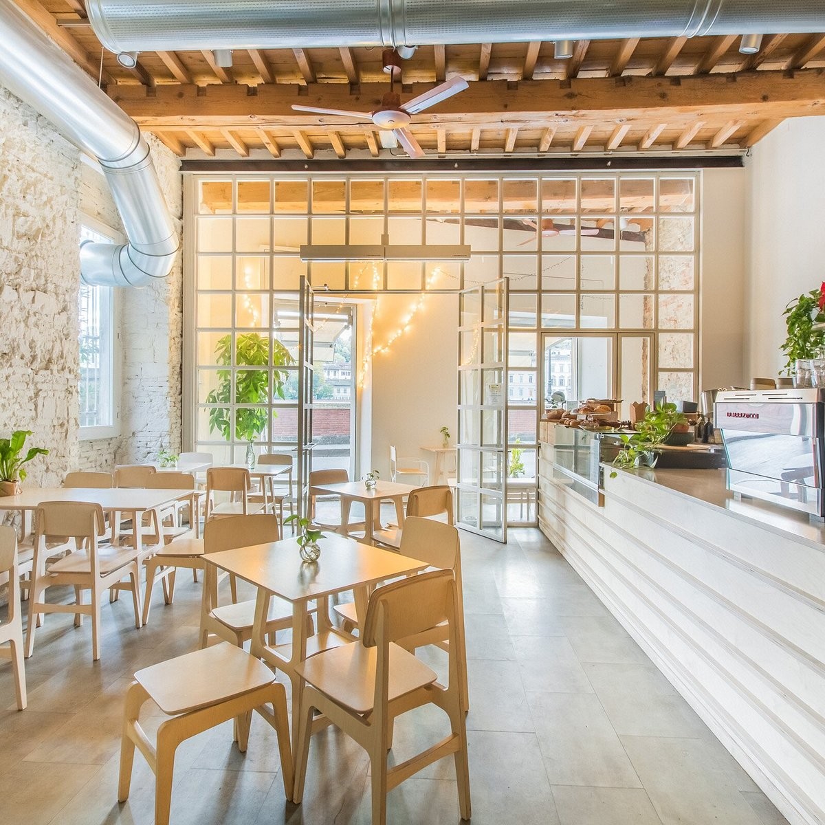 The bright, exposed stone and light wood dining room at Melaleuca, with glass doors open to the river