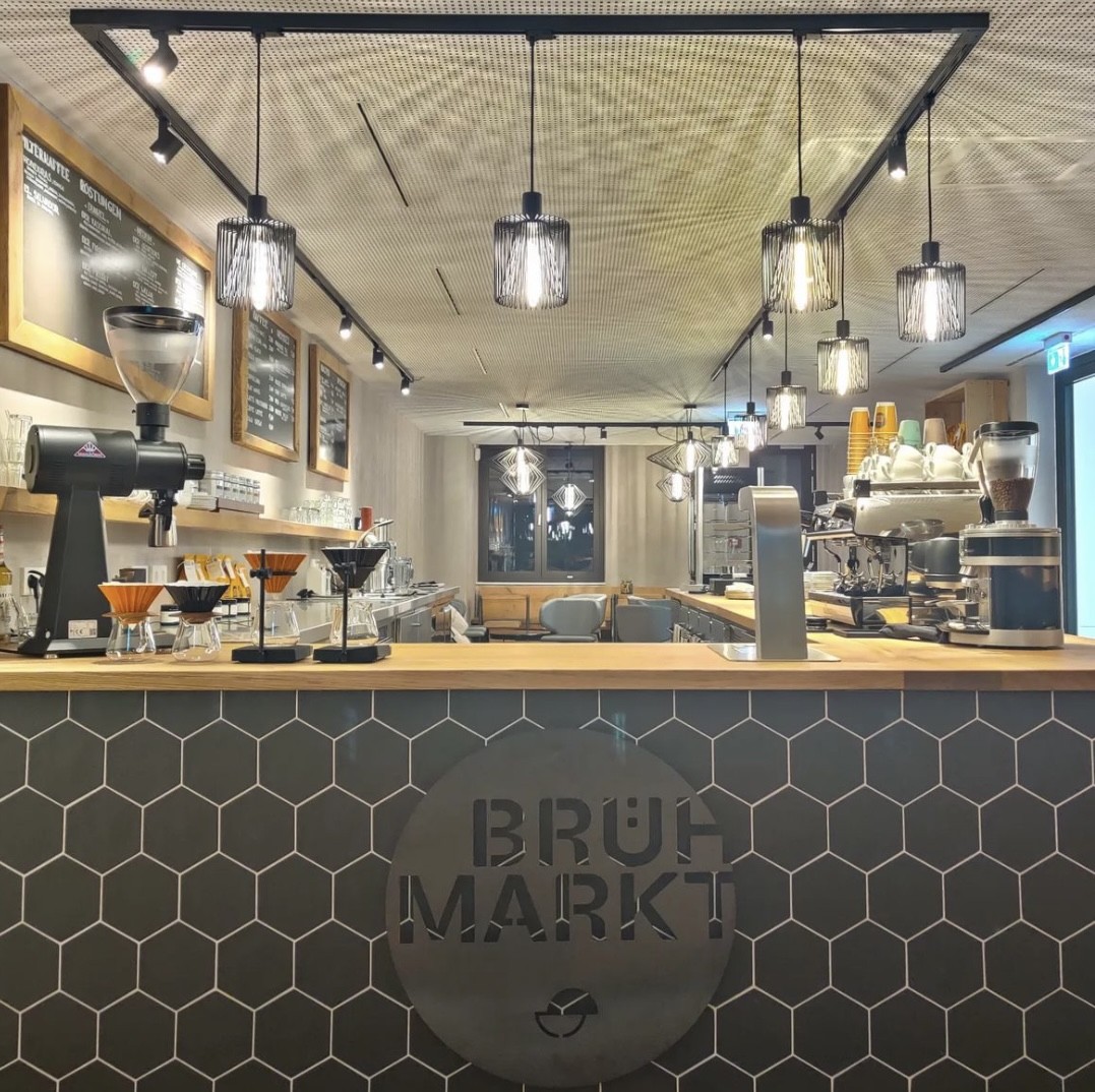 The Brühmarkt counter with its honeycomb tile logo, hanging pendant lights and a row of V60 pour over stations
