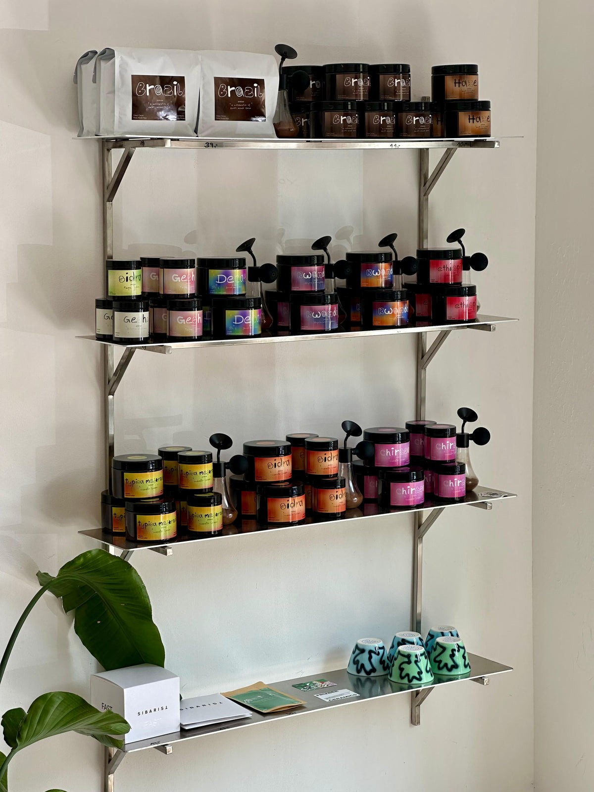 Metal shelving inside Ordinary Coffee Roasters' showroom, stacked with rows of labeled house roasted coffee tins and retail bags