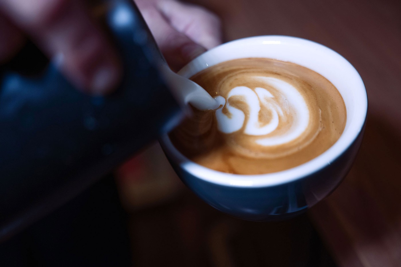 A close overhead view of milk being poured into an espresso to form latte art