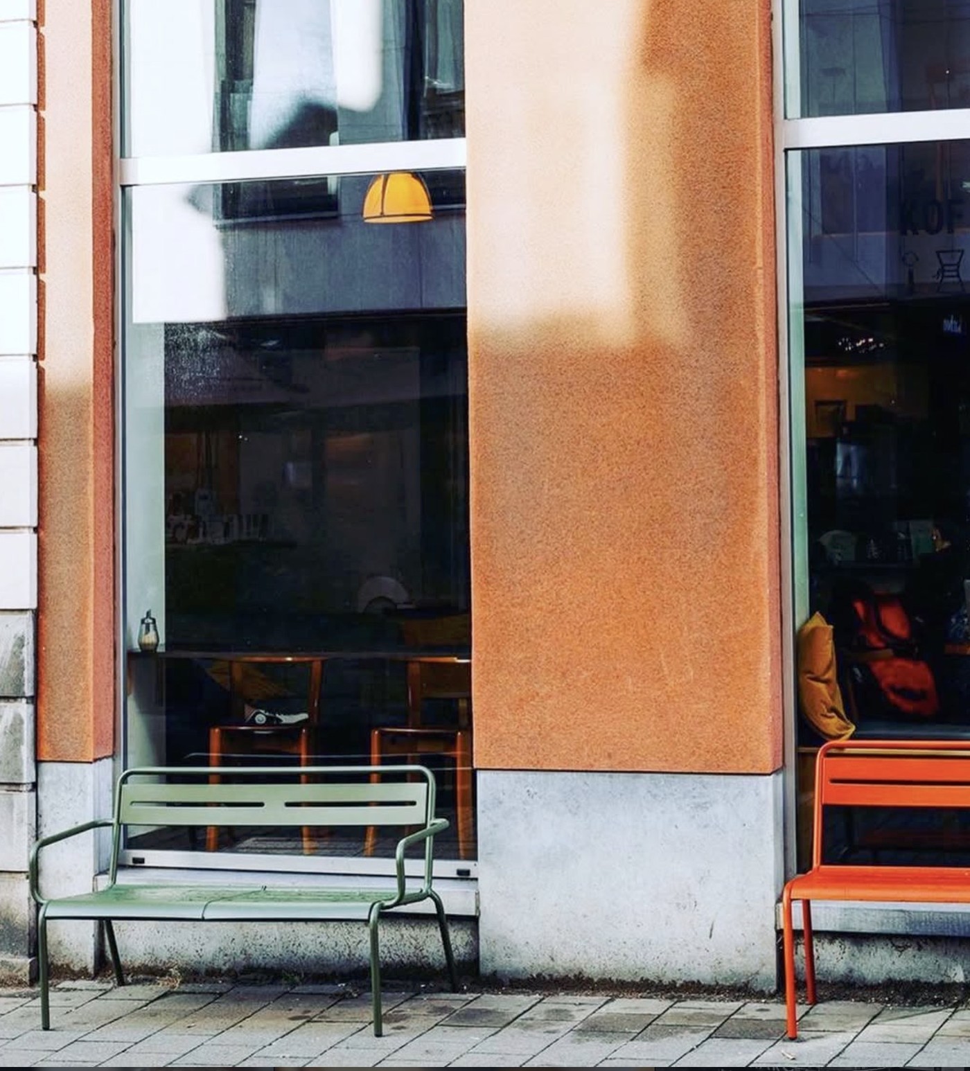 The terracotta pillared storefront of Koffeine with outdoor benches out front and cafe seating visible through the window