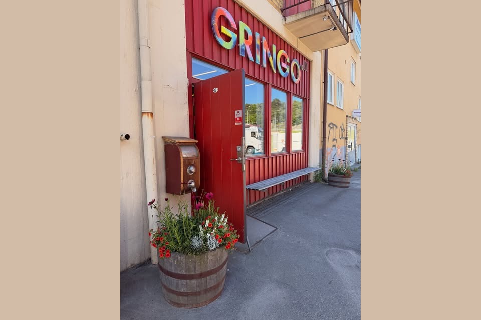 The colorful GRINGO storefront sign above a red painted door down an alley in Sandarna, Gothenburg