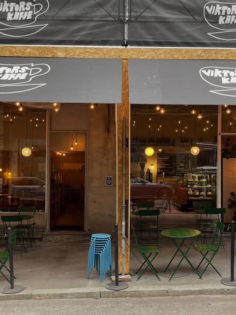 The Viktors Kaffe storefront on Geijersgatan at dusk, string lights glowing over green bistro tables outside